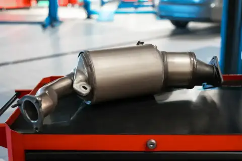 Nowy katalizator samochodowy, czyli GPF (Gasoline Particulate Filter), leży na wózku warsztatowym.